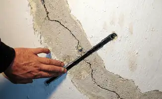 A wall with a large crack is being inspected by a professional in New Orleans, LA